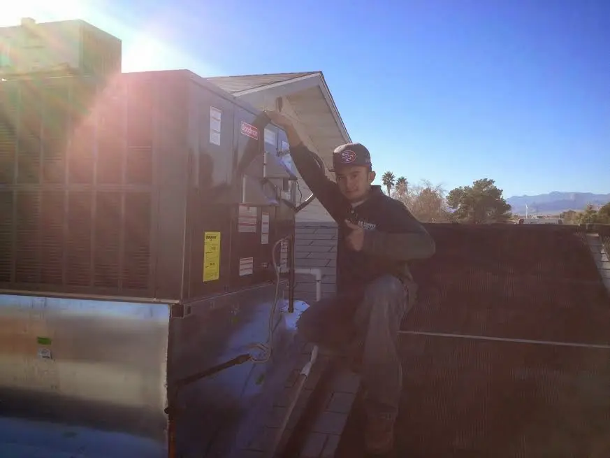 HVAC technician performing Air Duct Cleaning on a rooftop unit in Guilford